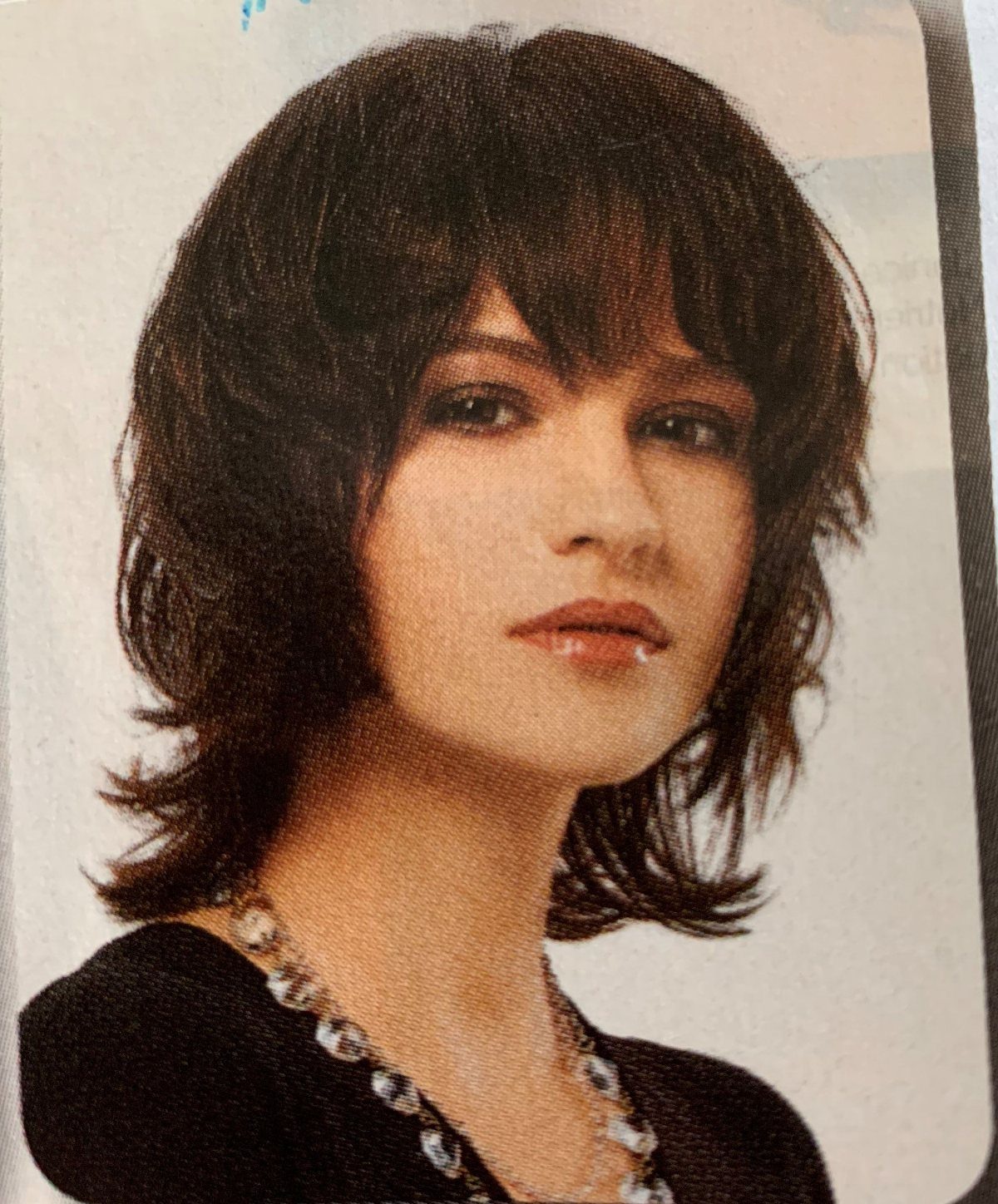 90s Hairstyles Short and 6 Ideas We Still Want to Copy 5 A woman with a dark, choppy layered hairstyle and wispy bangs wearing a silver necklace.