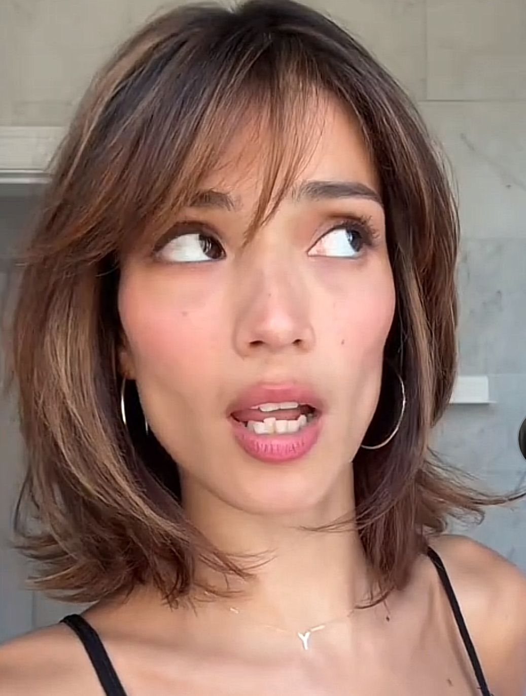 90s Hairstyles Short and 6 Ideas We Still Want to Copy 4 A woman with layered brown hair and soft side-swept bangs looking upwards.