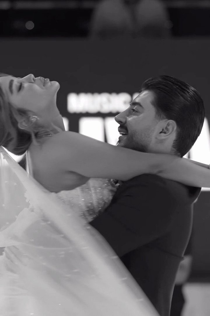 A bride leaning back in the arms of her smiling groom during a wedding dance.