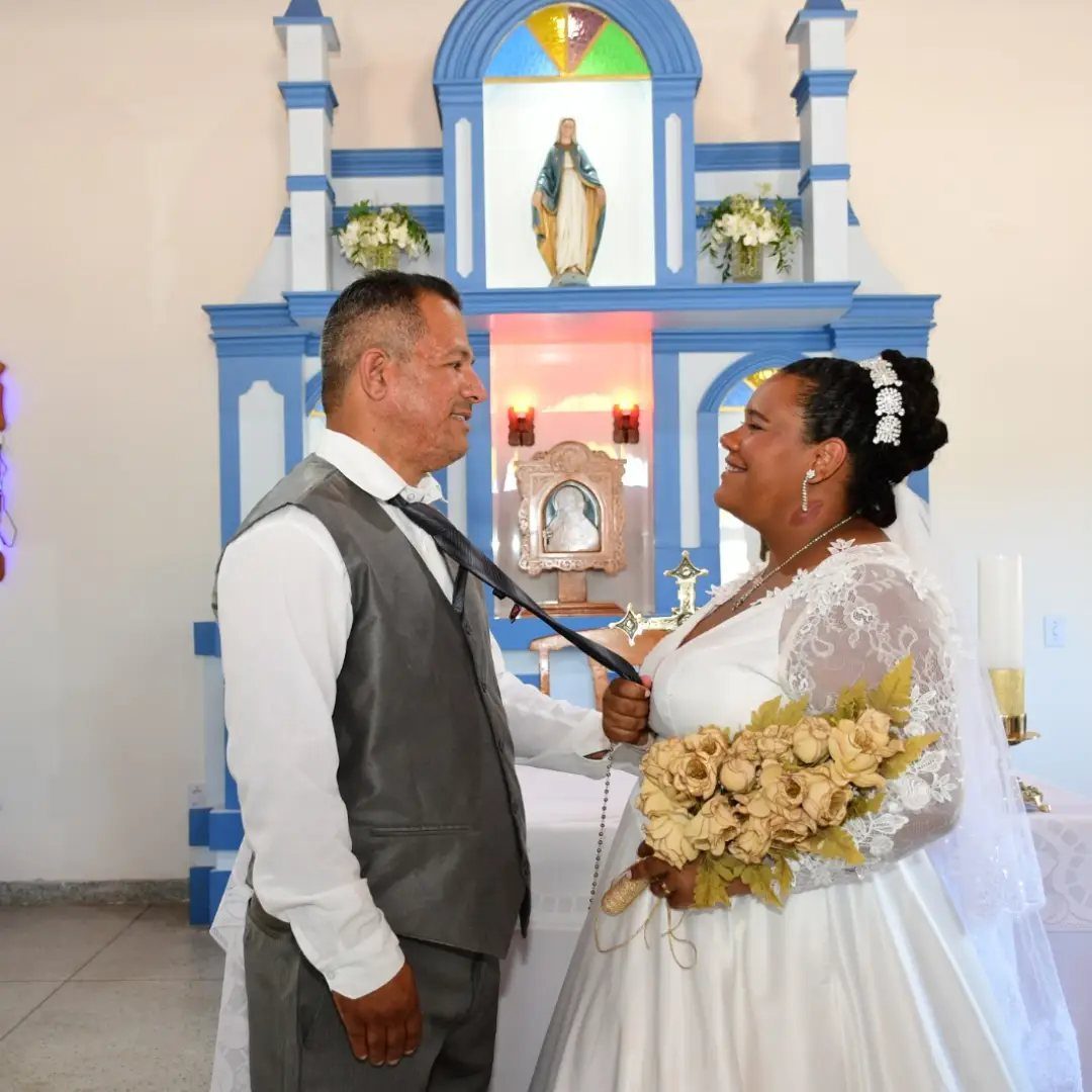 Bride smiling while playfully grabbing the groom's necktie inside a blue and white church.