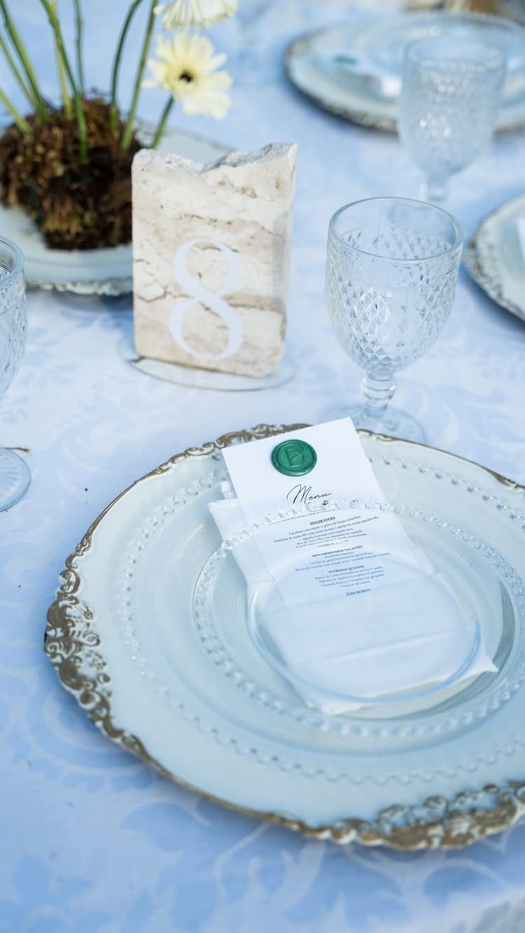A white table setting with a textured number eight, elegant plates, and clear glassware.