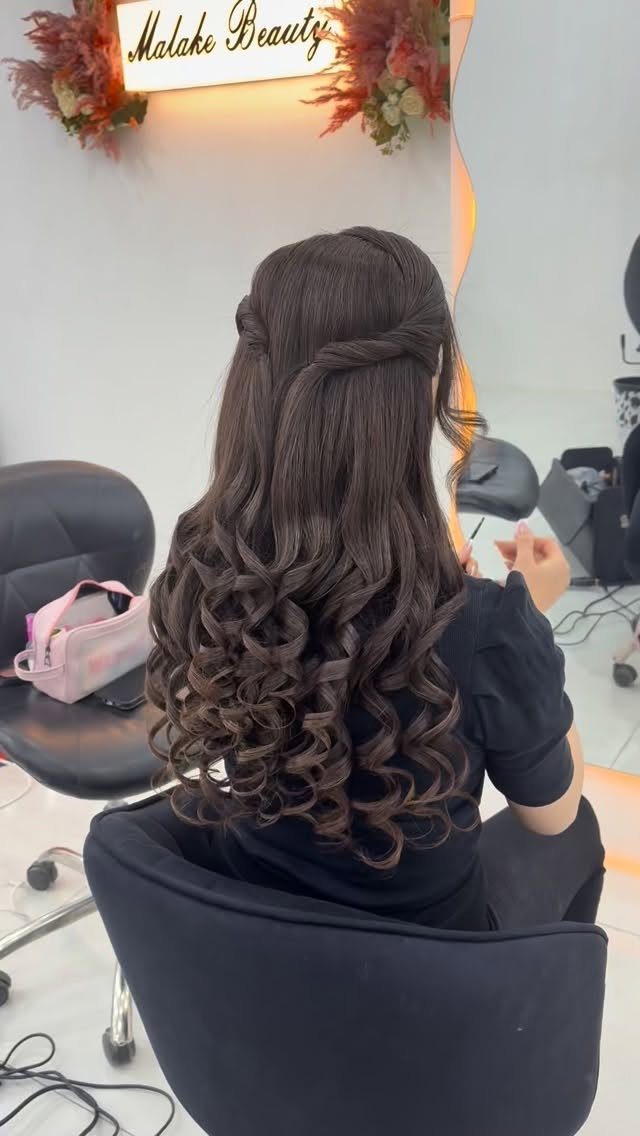 Woman with long dark hair in a half-up twisted hairstyle with voluminous curls.