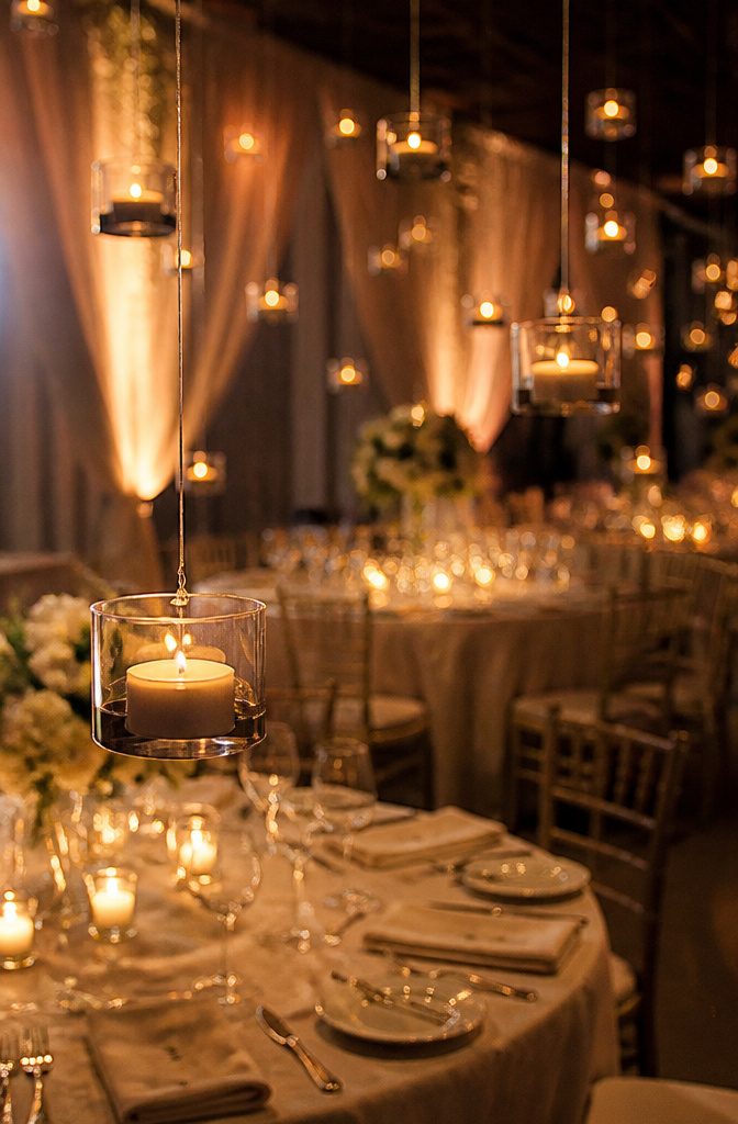 Battery-powered tea lights hanging above tables at a wedding.