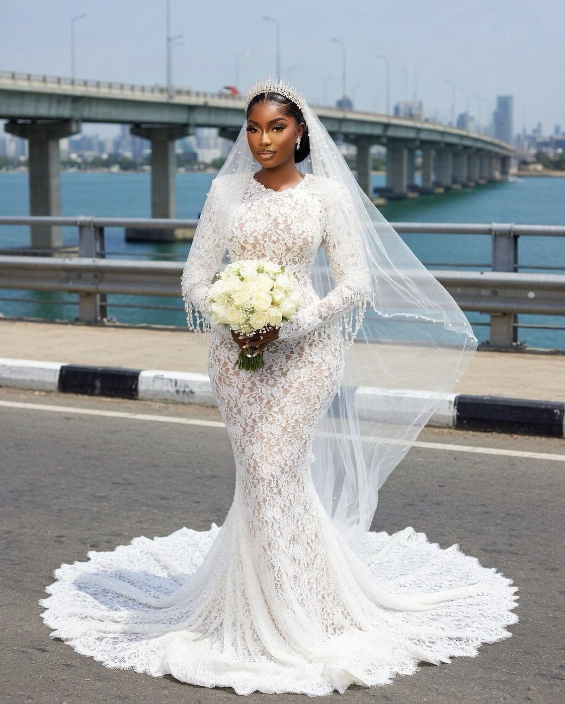 A woman wearing a white lace mermaid wedding dress and veil holding a bouquet.