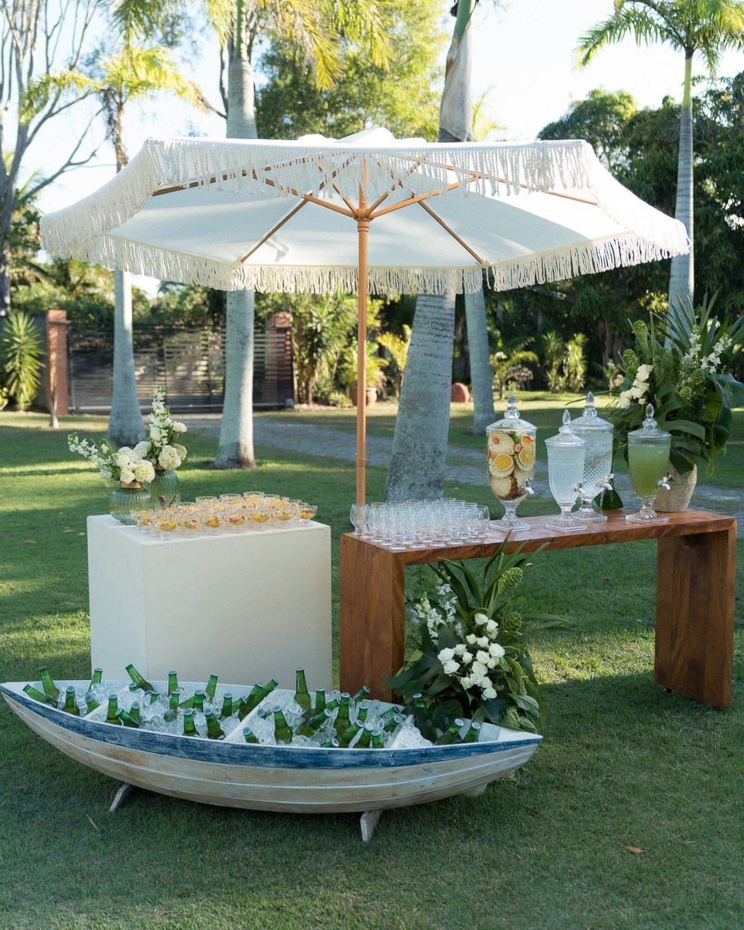 Outdoor beverage station with drink dispensers, glassware, and iced bottles in a small boat.