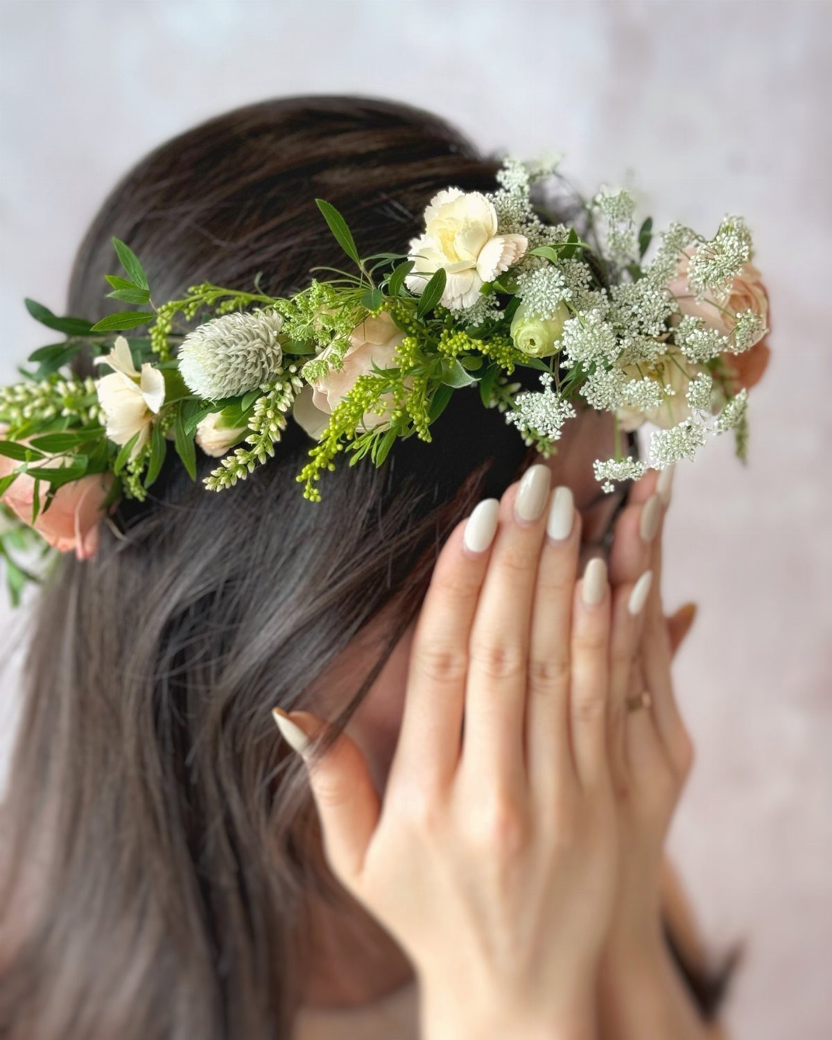 A woman wearing a beautiful floral crown made of roses and baby's breath.