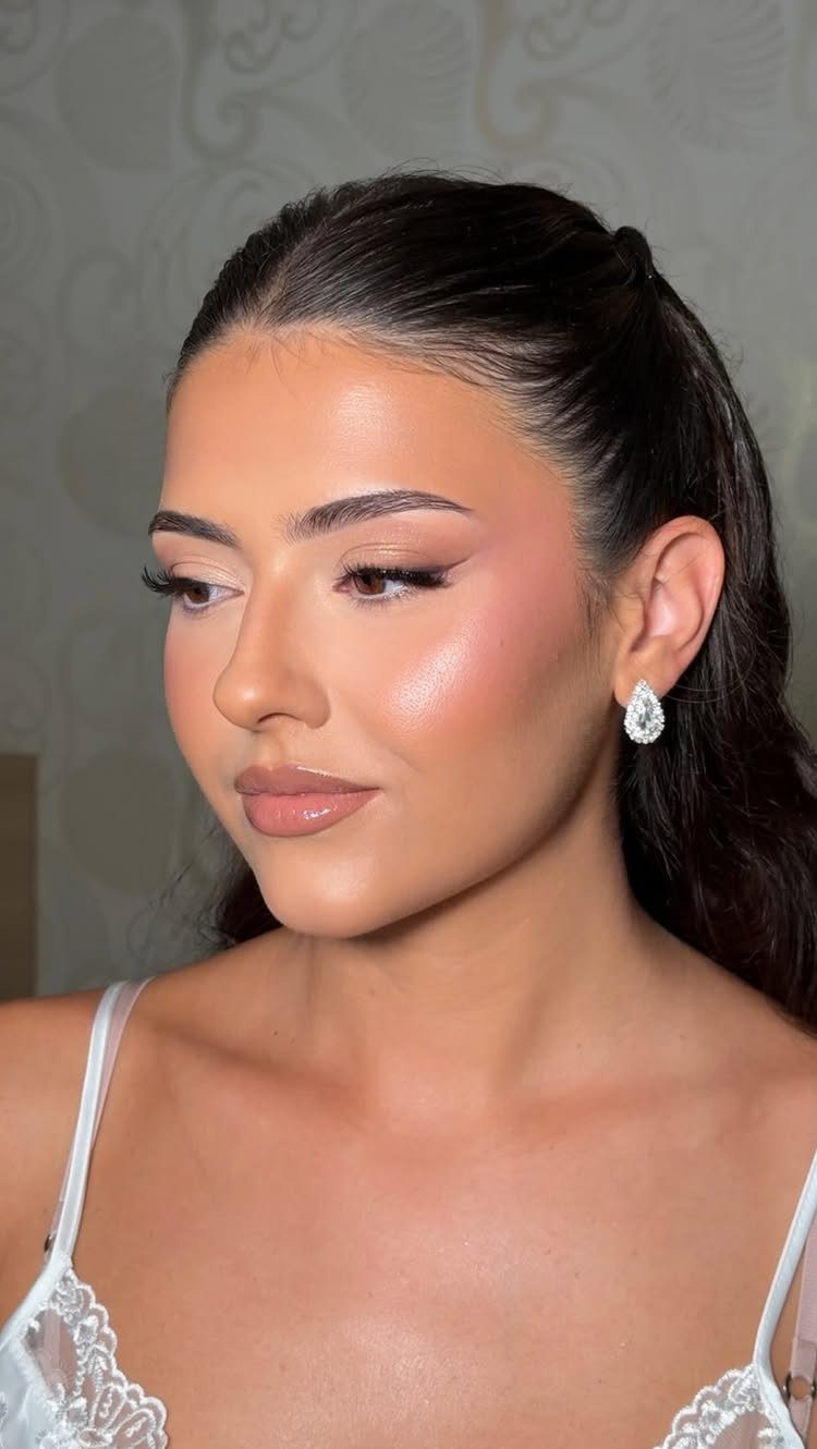 A young woman with soft brown eyeshadow, winged eyeliner, and glossy lips looking away.