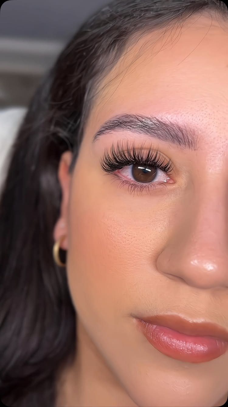 Close-up of a woman's face showcasing long, voluminous eyelashes and groomed eyebrows.