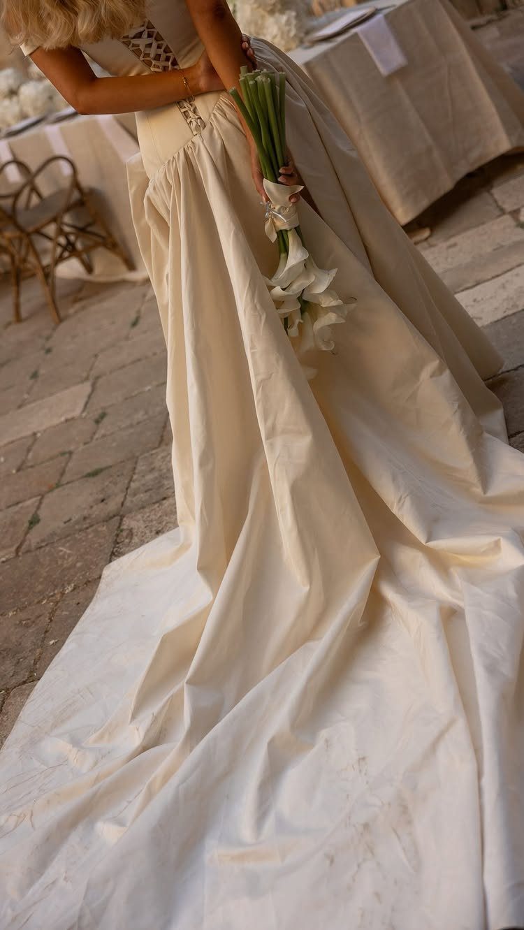 An ivory wedding gown with a long train and a white calla lily bouquet.