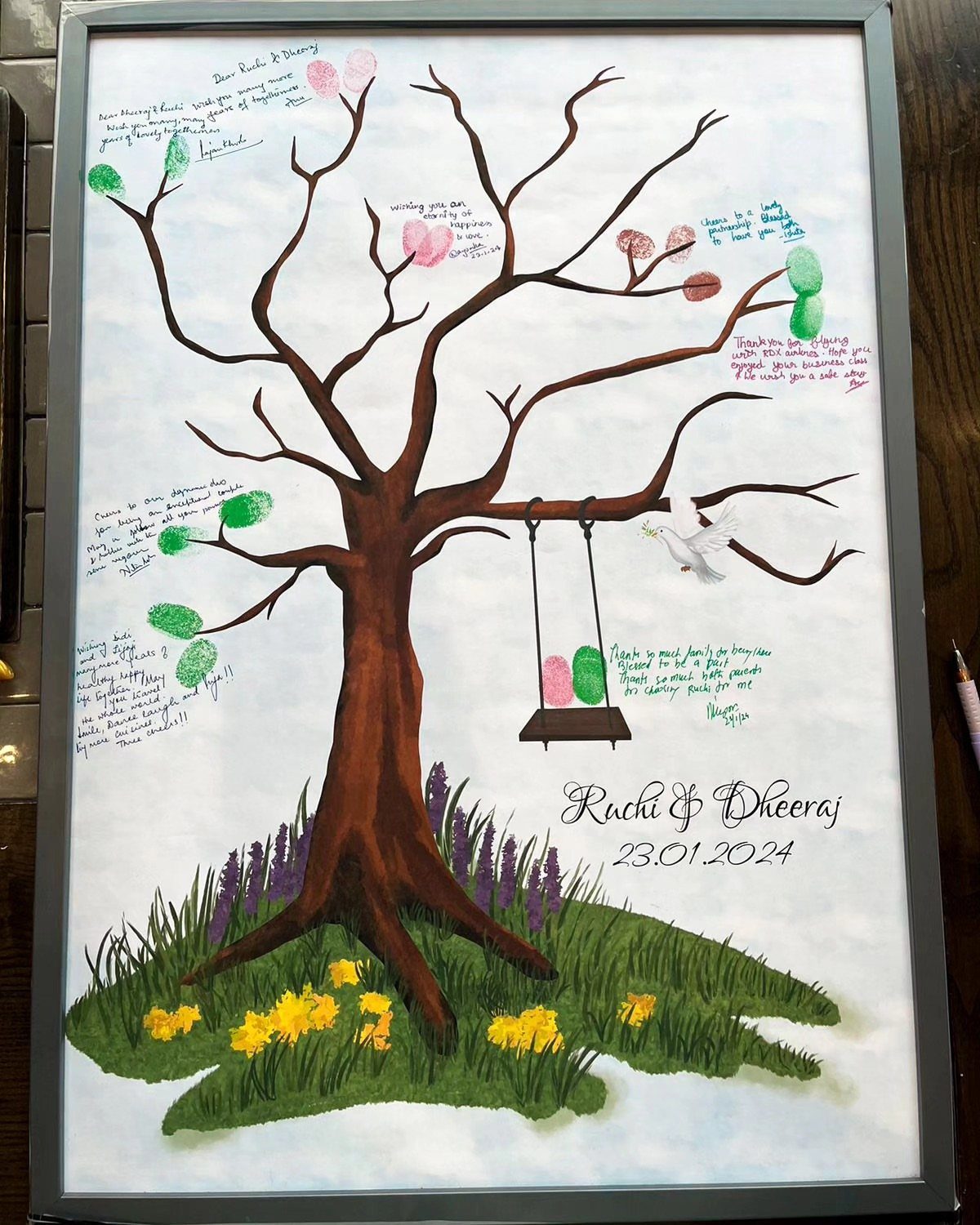 A framed thumbprint tree painting with colorful fingerprints acting as leaves and handwritten messages.