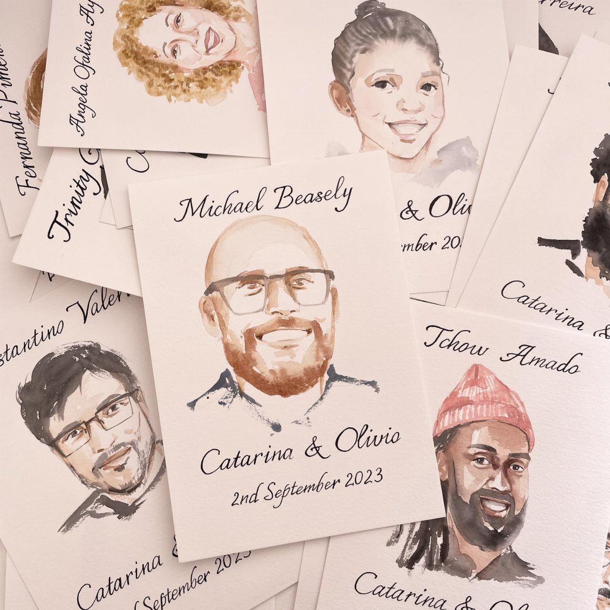 Watercolor portrait cards with names and dates scattered on a white surface.