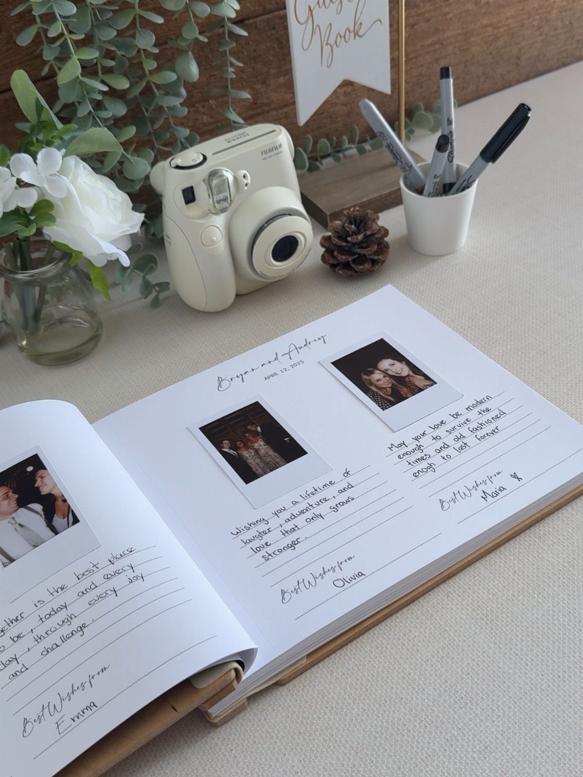 An open guest book with Polaroid photos and handwritten messages next to an instant camera.