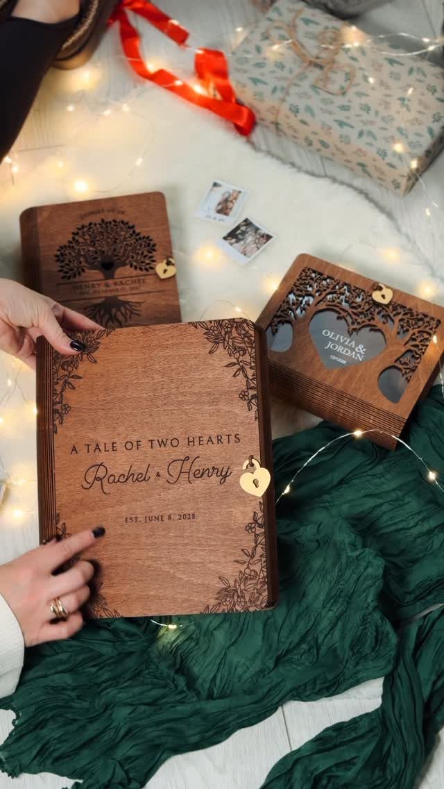 Engraved wooden keepsake boxes and a book resting on a white surface with fairy lights.