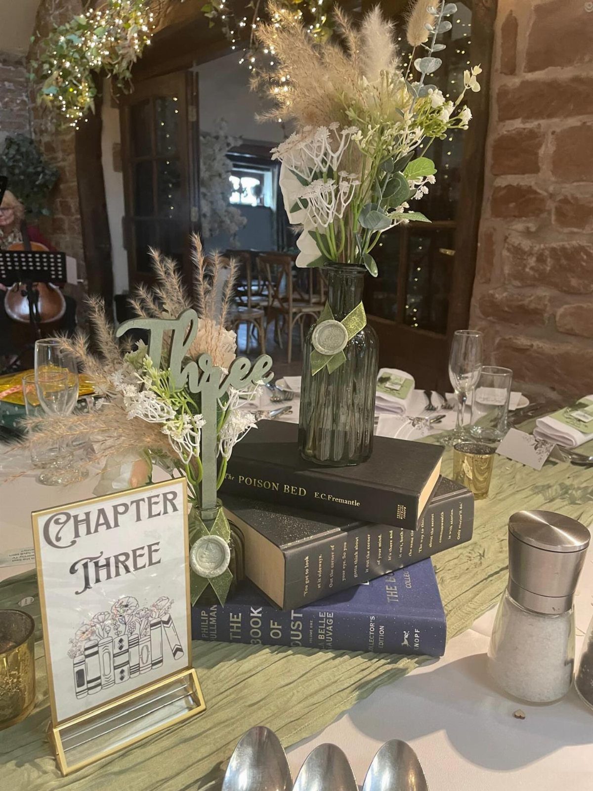 Vintage books stacked on a table serving as a centerpiece with a floral glass bottle.