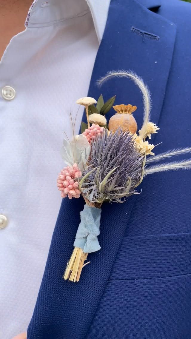 A dried floral boutonniere pinned to the lapel of a blue suit jacket.