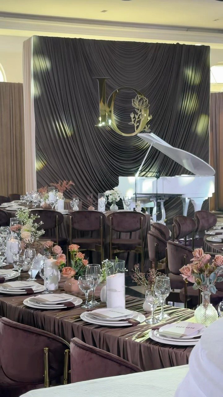 Wedding reception tables set with chocolate brown linens, ivory plates, and peach floral arrangements.