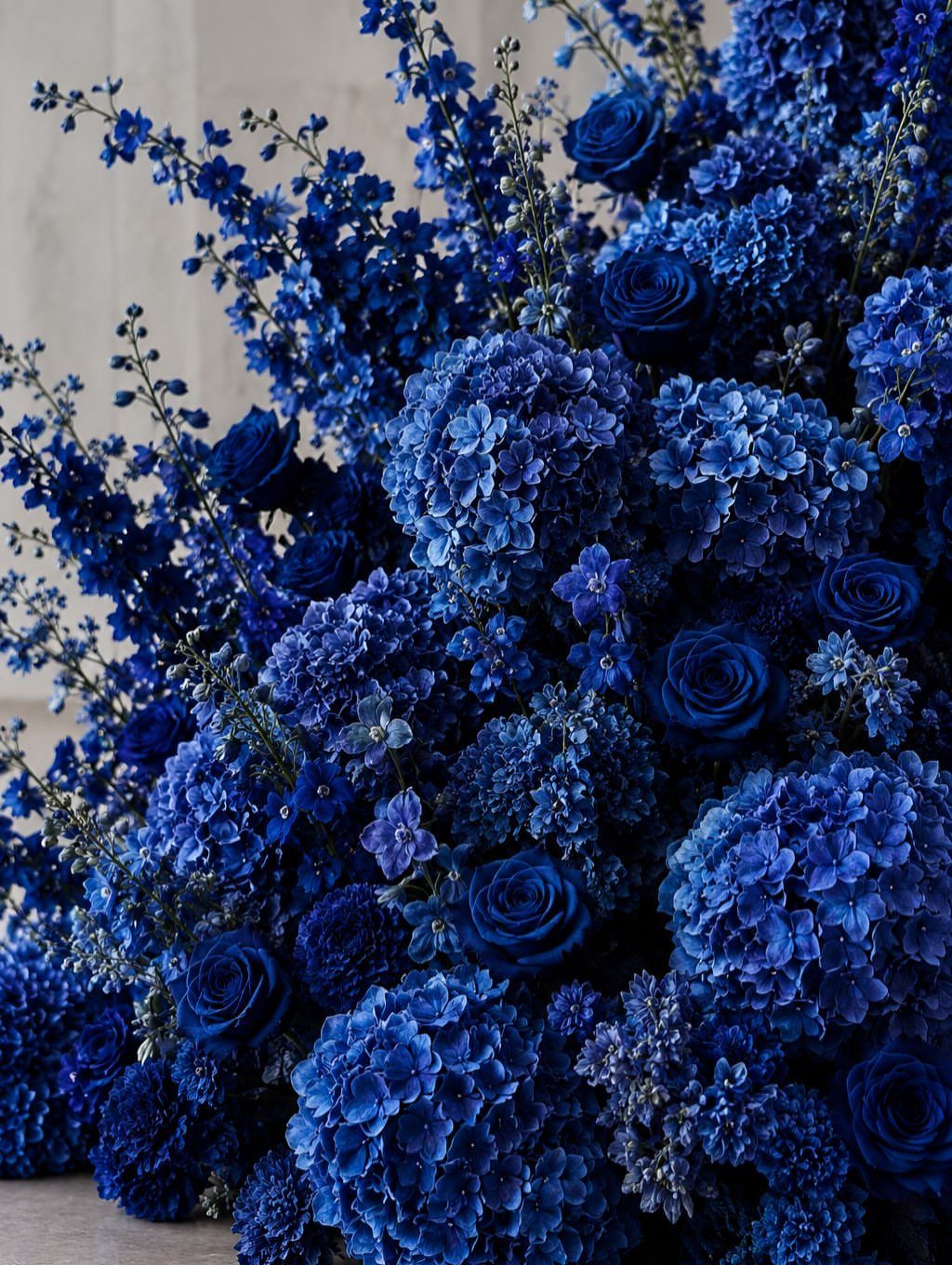 Deep midnight blue roses and hydrangeas arranged in a lush, dense floral bouquet.
