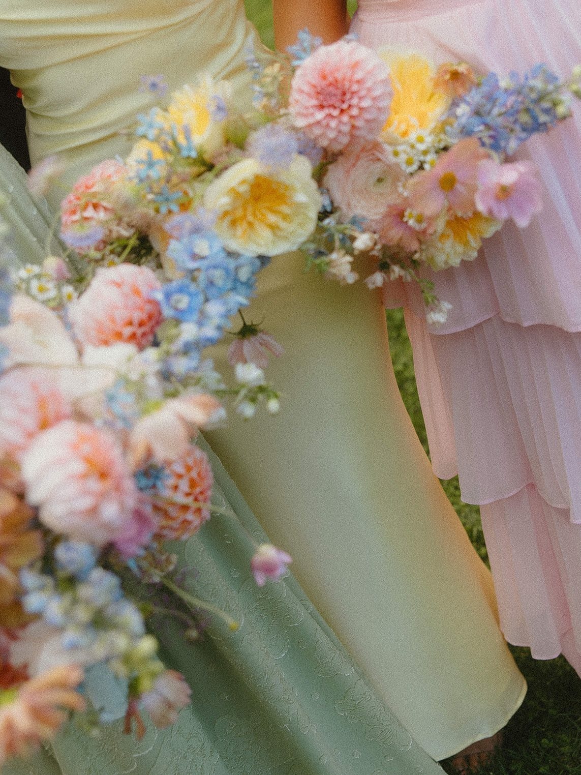 Floral bouquets with pink, yellow, and blue flowers held against pastel dresses.