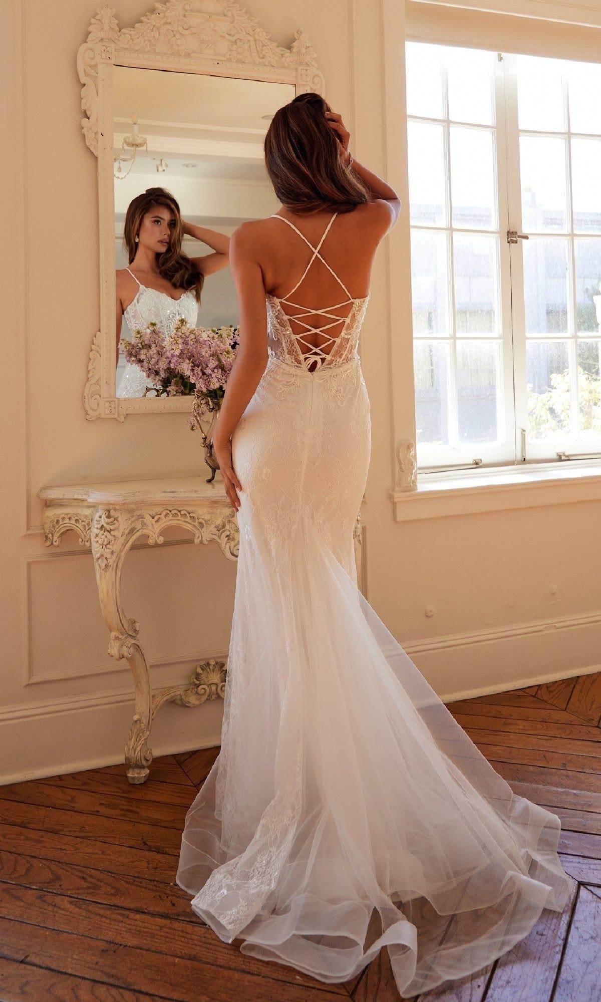 Tight Lace Wedding Dress: 8 Fitted Styles to Shape the Day 6 Woman in a white mermaid wedding dress with a lace-up corset back standing before a mirror.