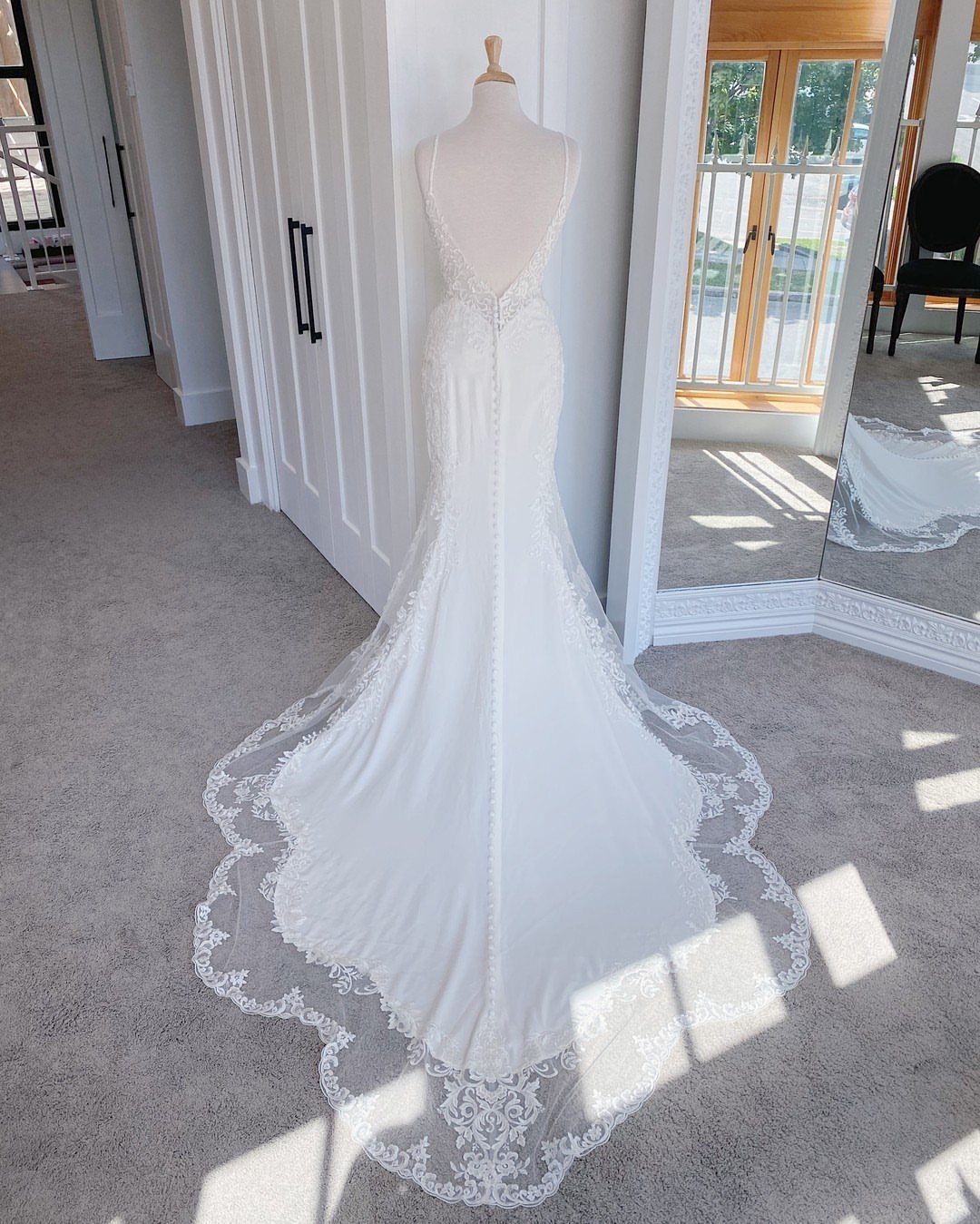 Tight Lace Wedding Dress: 8 Fitted Styles to Shape the Day 8 A white mermaid wedding dress with a long scalloped lace train displayed on a mannequin.