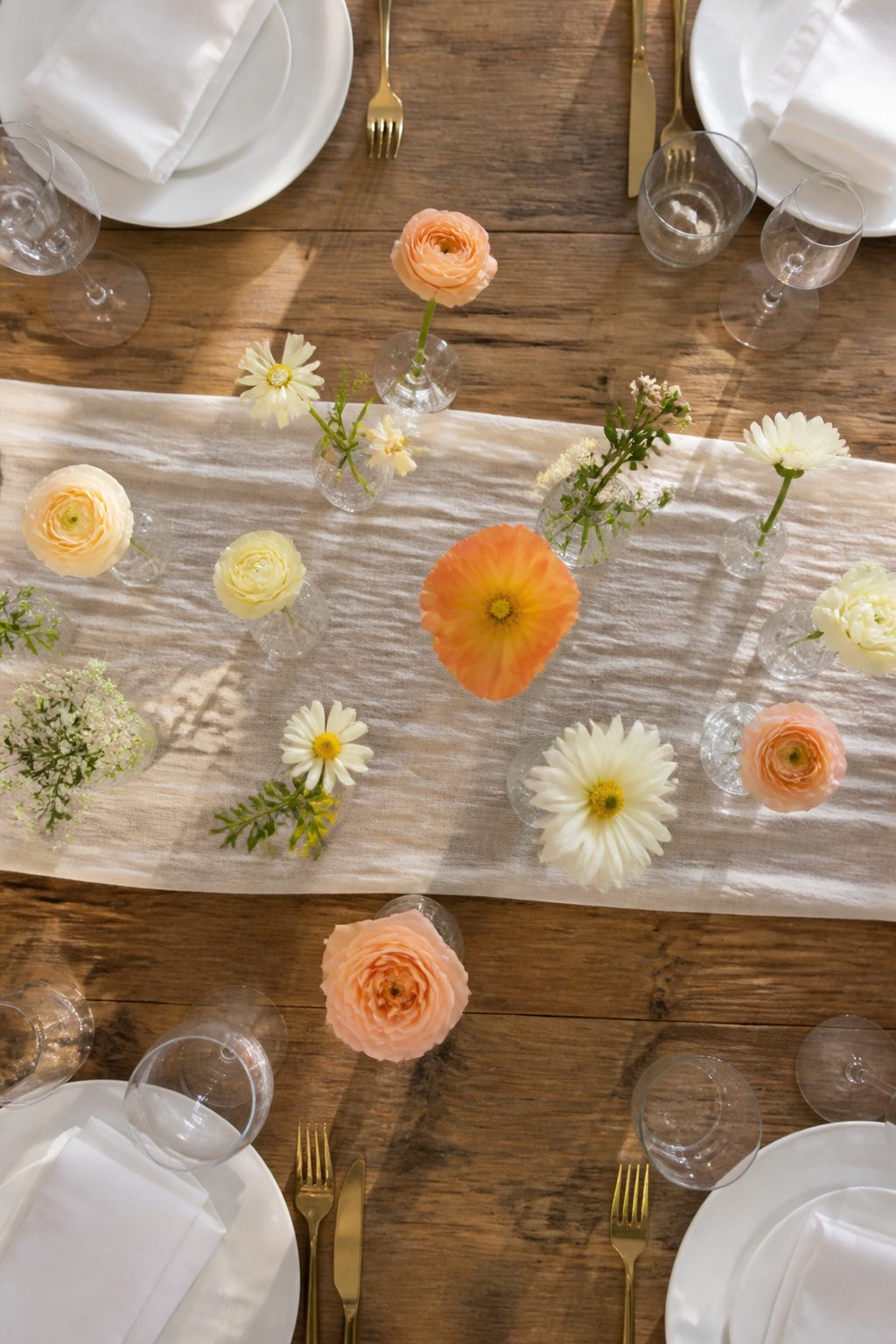 Cluster of small bud vases with flowers on a table.