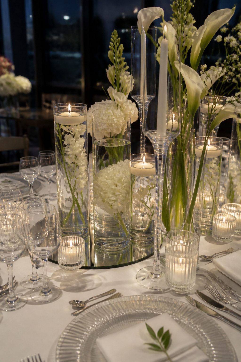 Glass cylinders and white flowers on a wedding table.