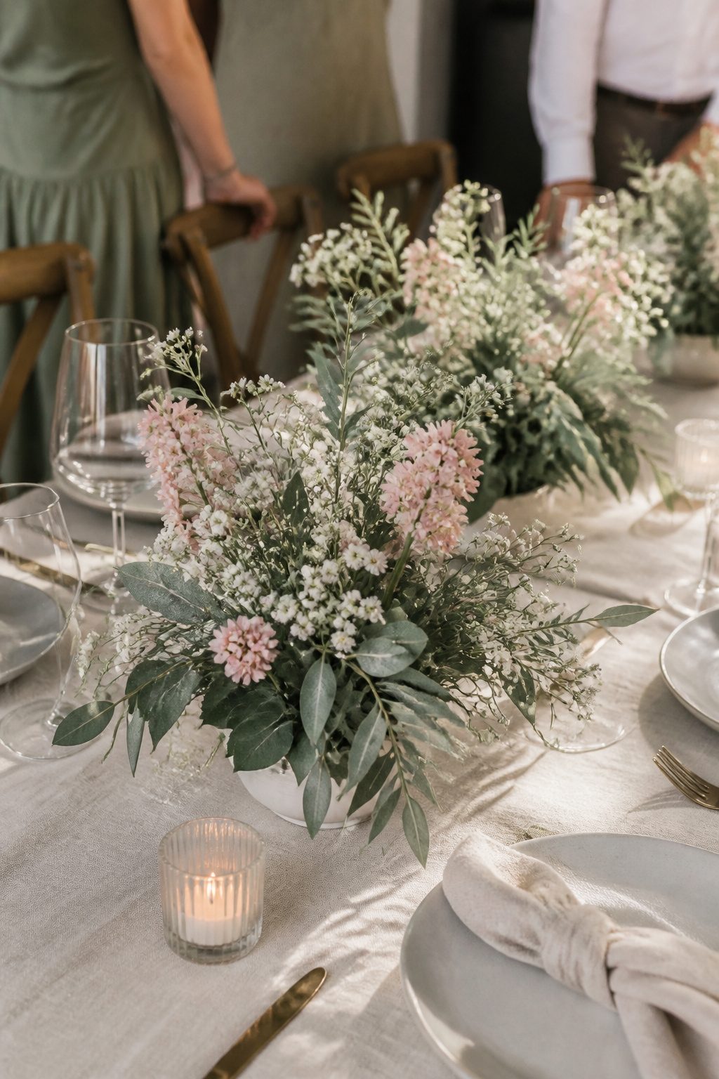 Sage foliage with Baby's Breath and pink flowers in a centerpiece.