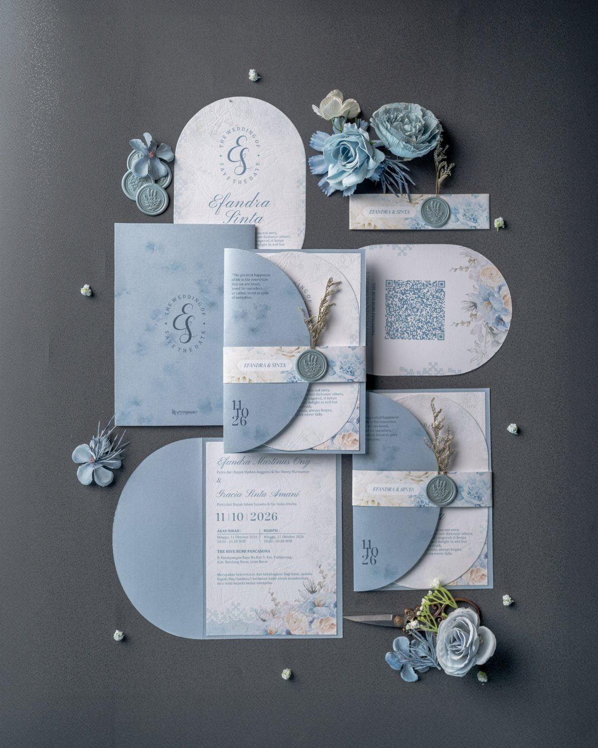 Dusty blue wedding invitations and stationery set with floral patterns and blue silk flowers.