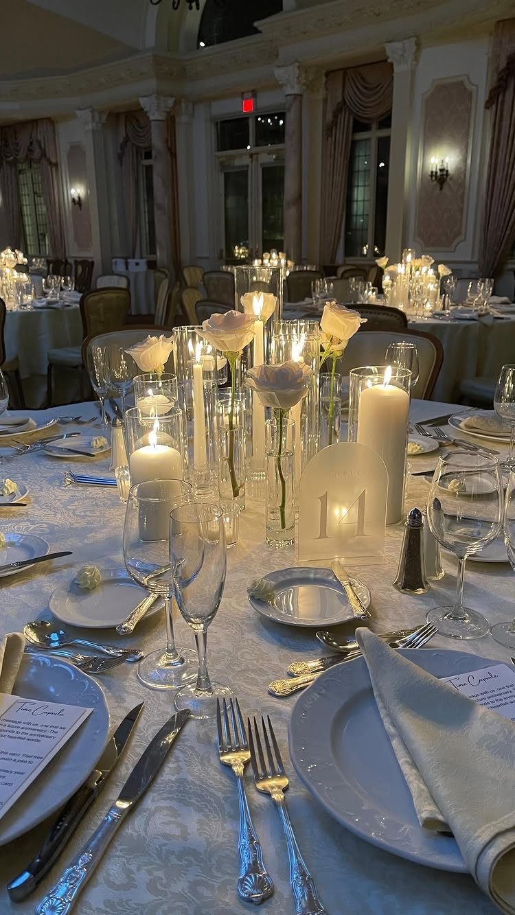 White roses and candles illuminating an elegant wedding reception table setting.
