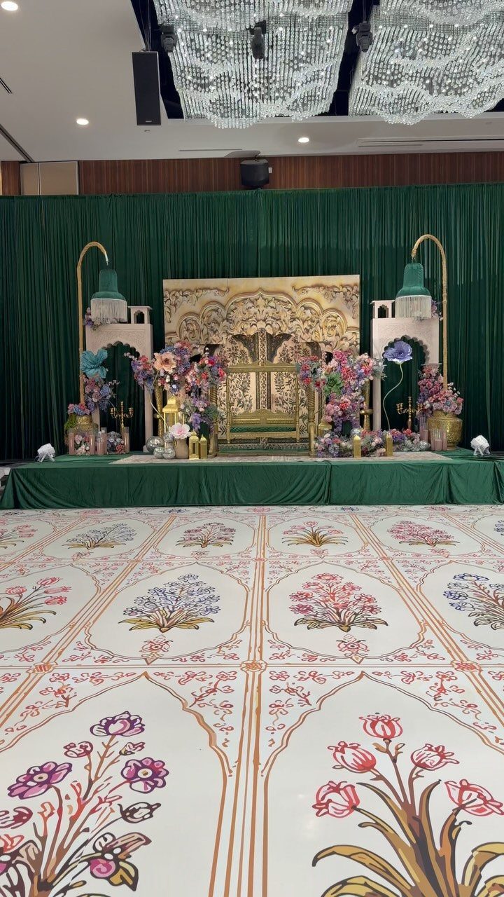Patterned dance floor with floral designs in front of a decorated wedding stage.