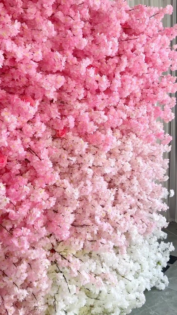A dense wall of pink and white artificial cherry blossom flowers.