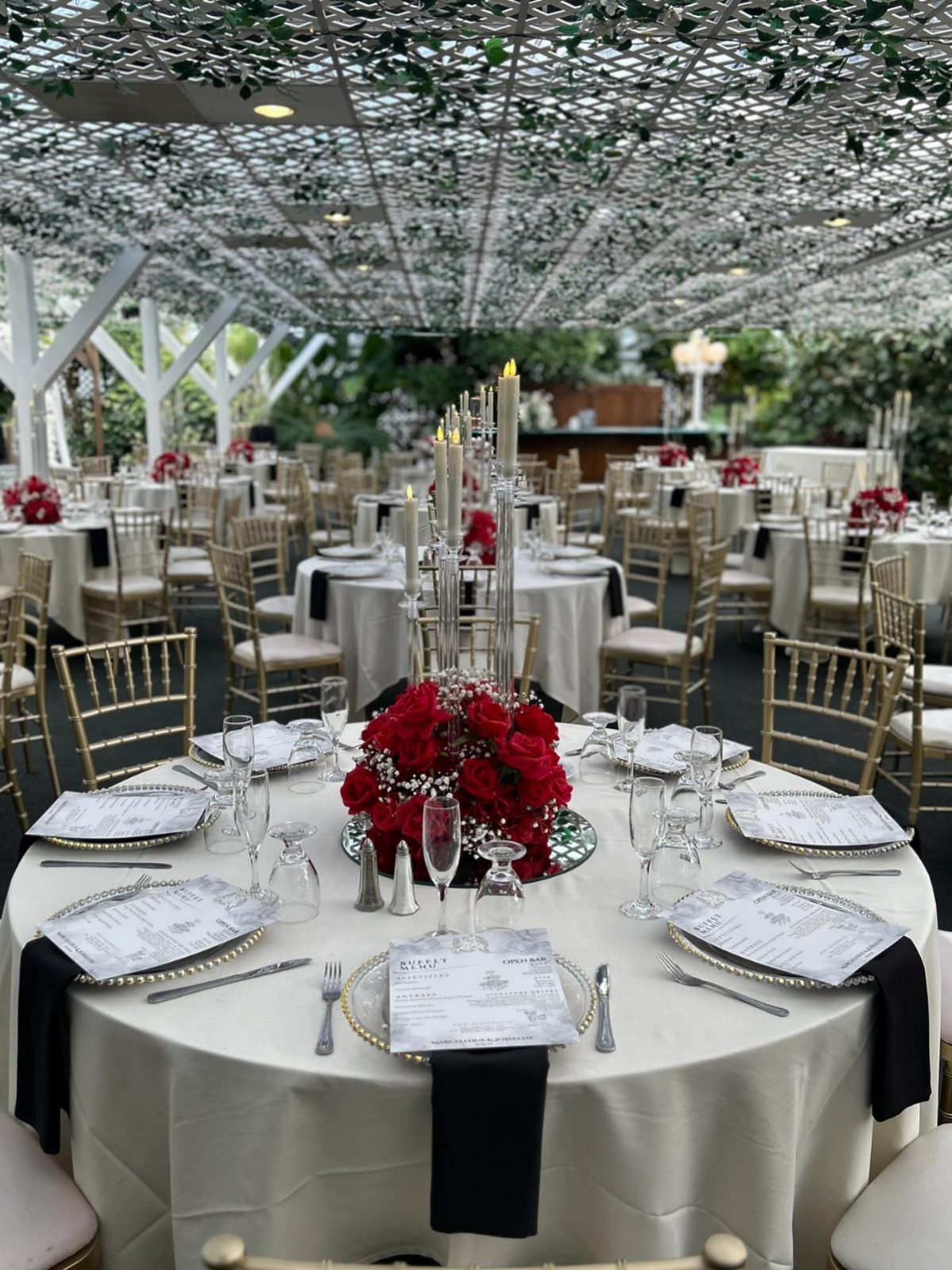 Wedding Decor with Red Roses: 9 Concepts from Pew Markers to Car Details 2 A formal wedding table setting featuring a centerpiece of red roses and tall white taper candles.