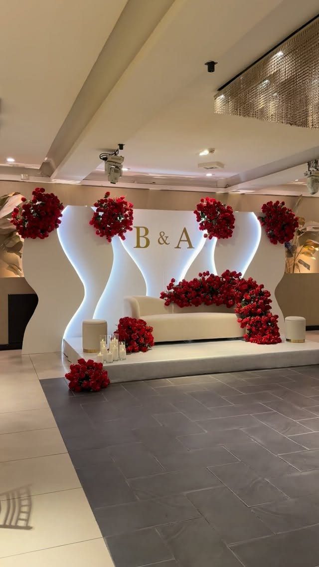 A white wavy wedding stage with red flowers and glowing LED backlighting.