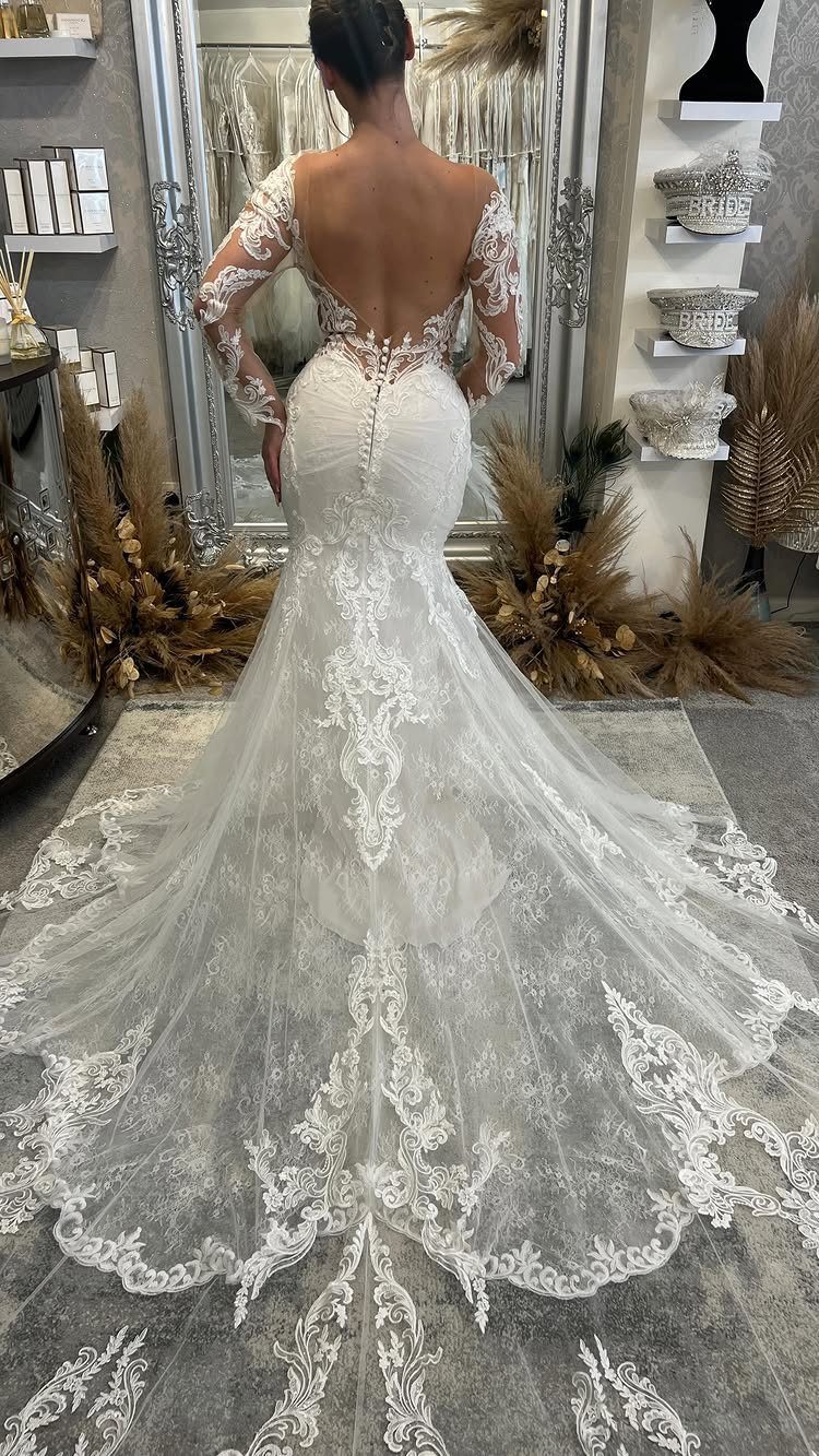 7 Wedding Dresses for Winter Brides That Balance Warmth and Style 6 Woman wearing a white lace mermaid wedding dress with long sleeves and a long train.
