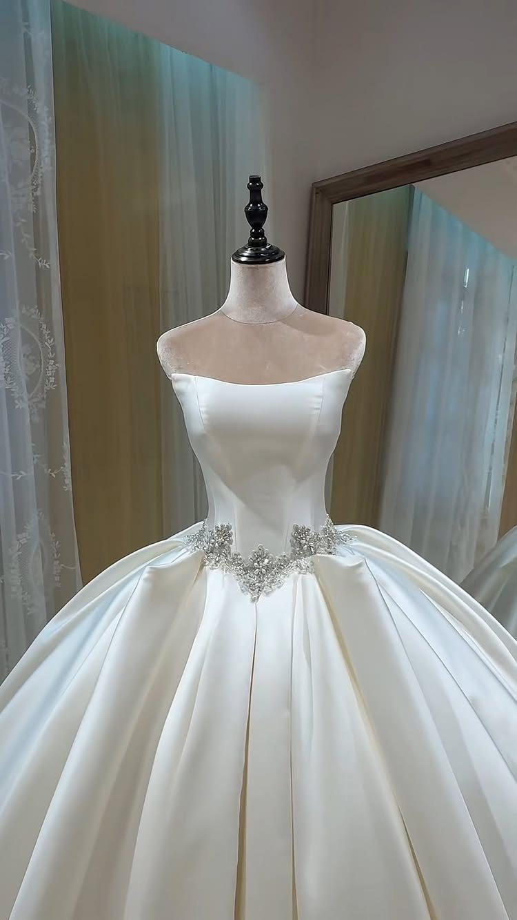 7 Wedding Dresses for Winter Brides That Balance Warmth and Style 1 A white satin ballgown with crystal waist embellishments displayed on a mannequin.