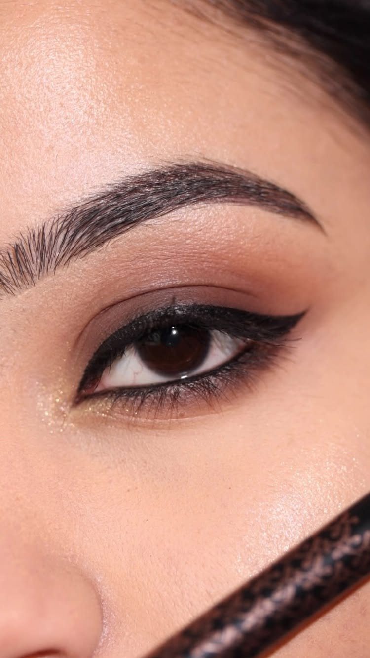 Close-up of a person's eye with warm brown eyeshadow and black winged eyeliner.