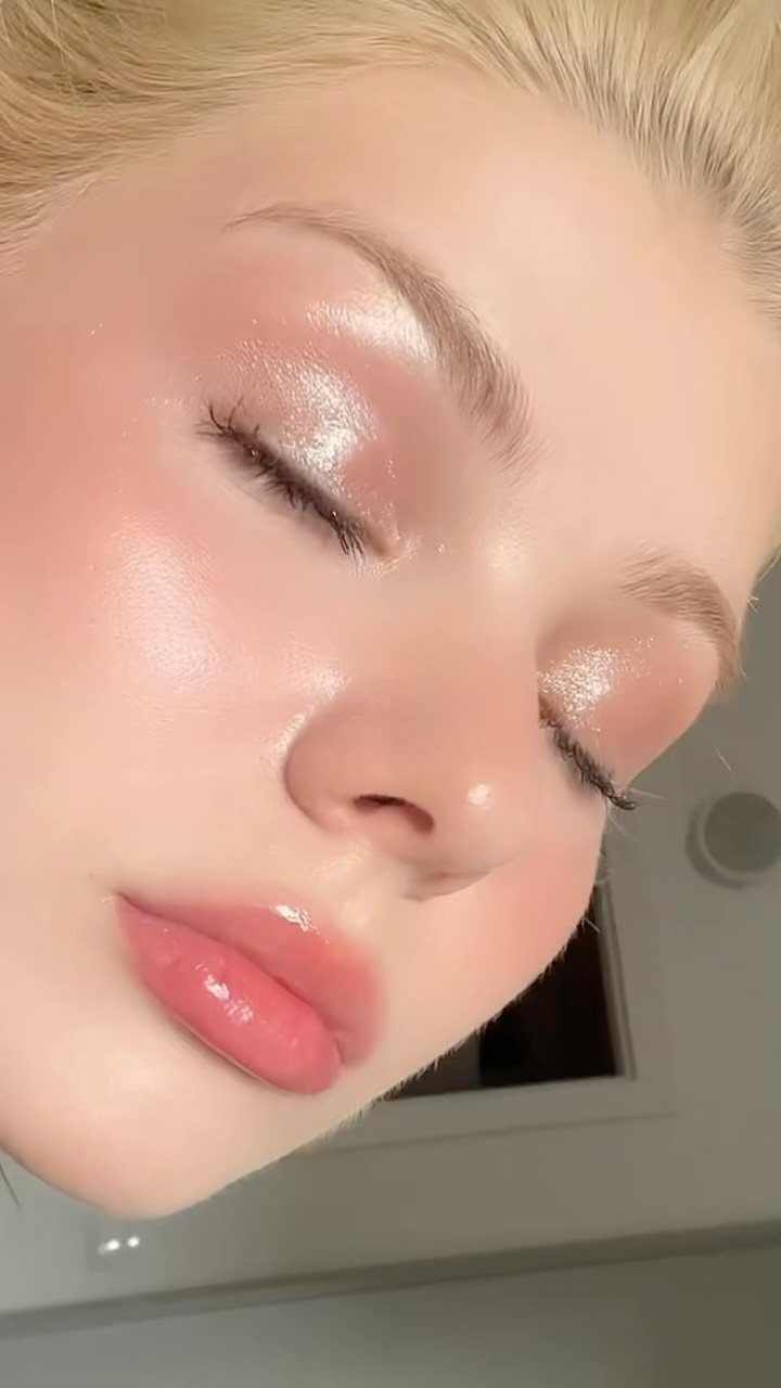 Close-up of a person wearing shimmering rose gold eyeshadow and glossy pink lips.