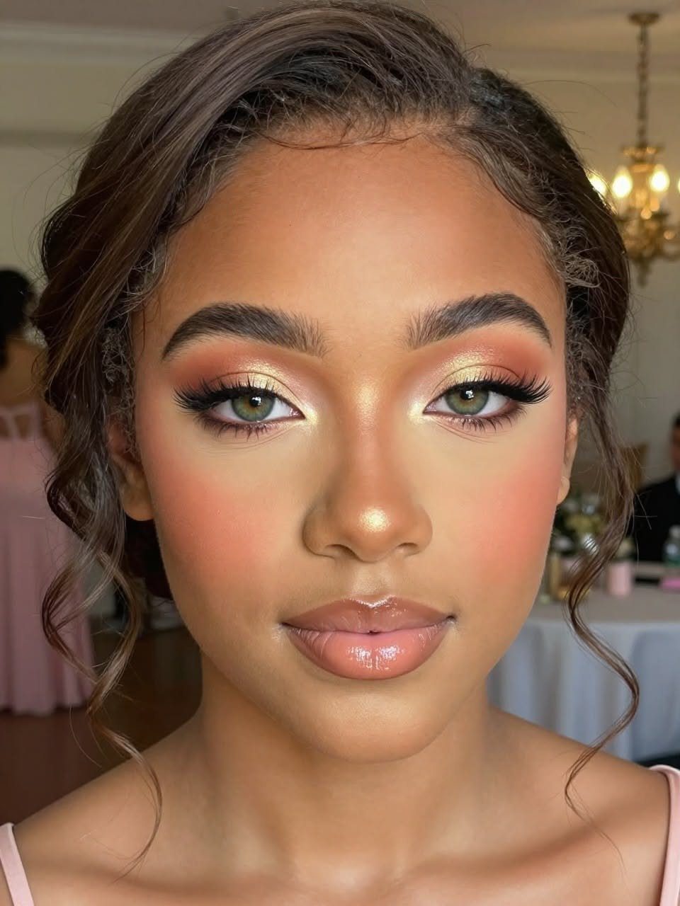 A young woman with shimmering peach and gold eyeshadow and elegant updo hairstyle.