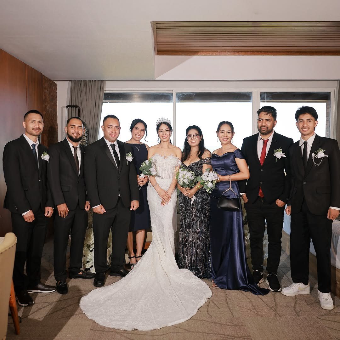 12 Wedding Groom Photos to Capture: From Getting Ready to Golden Hour 10 A wedding party including a bride, bridesmaids, and groomsmen posing together indoors.