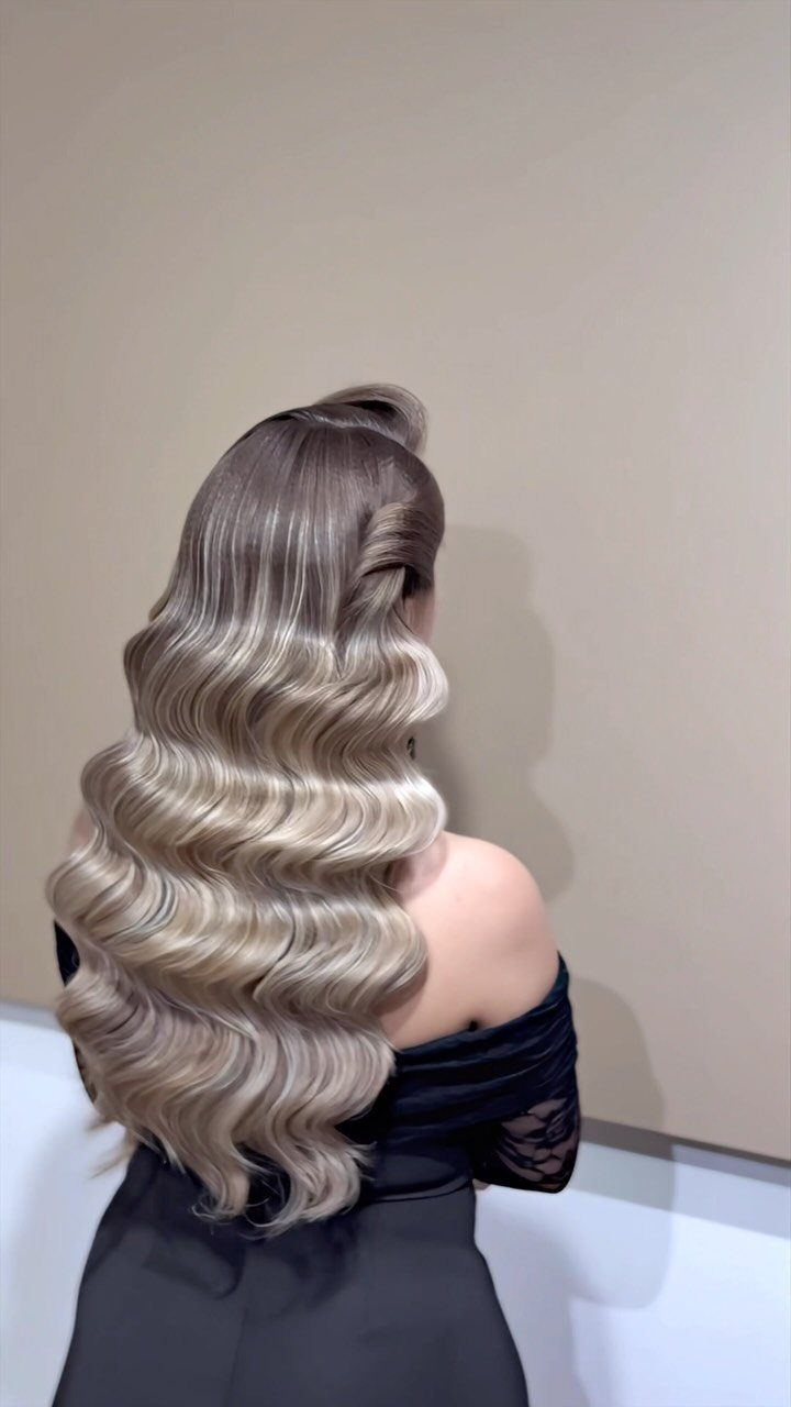 5 Wedding Hair Inspo Ideas for Brides From Loose Curls to Hollywood Waves 4 Long blonde hair styled in voluminous, structured Hollywood waves against a beige background.