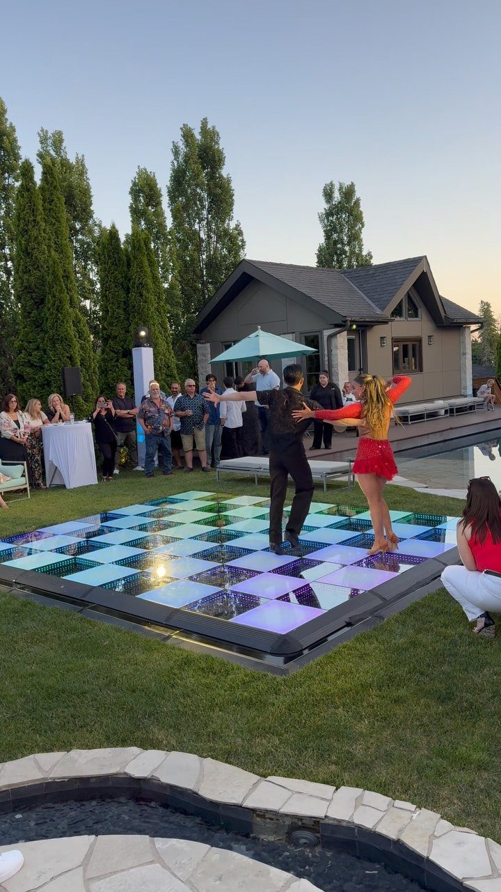 A couple dancing on a glowing checkered LED dance floor in a backyard setting.