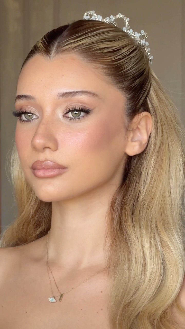 Woman with neutral bridal makeup, blonde hair, and a sparkling tiara looking slightly away.