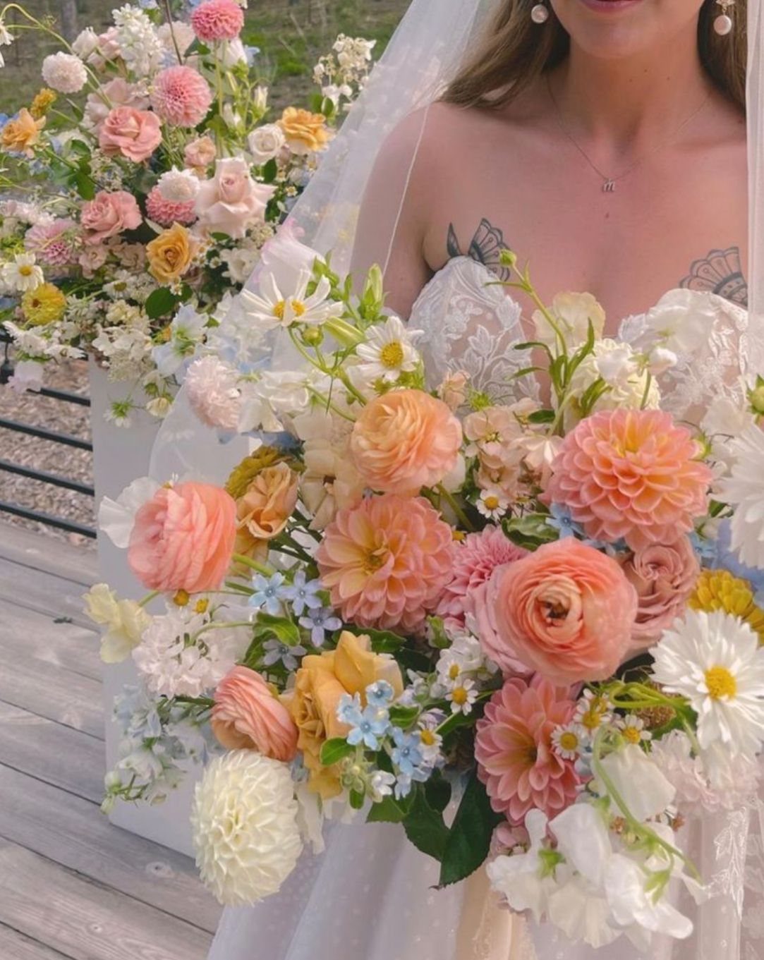 A bride holding a large bouquet of pastel peach, pink, and white flowers.