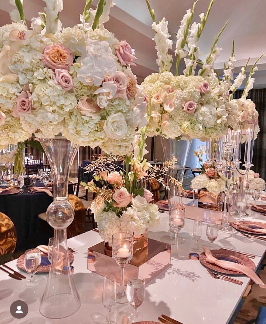 Large white and pink floral centerpieces on a wedding table with rose gold accents.