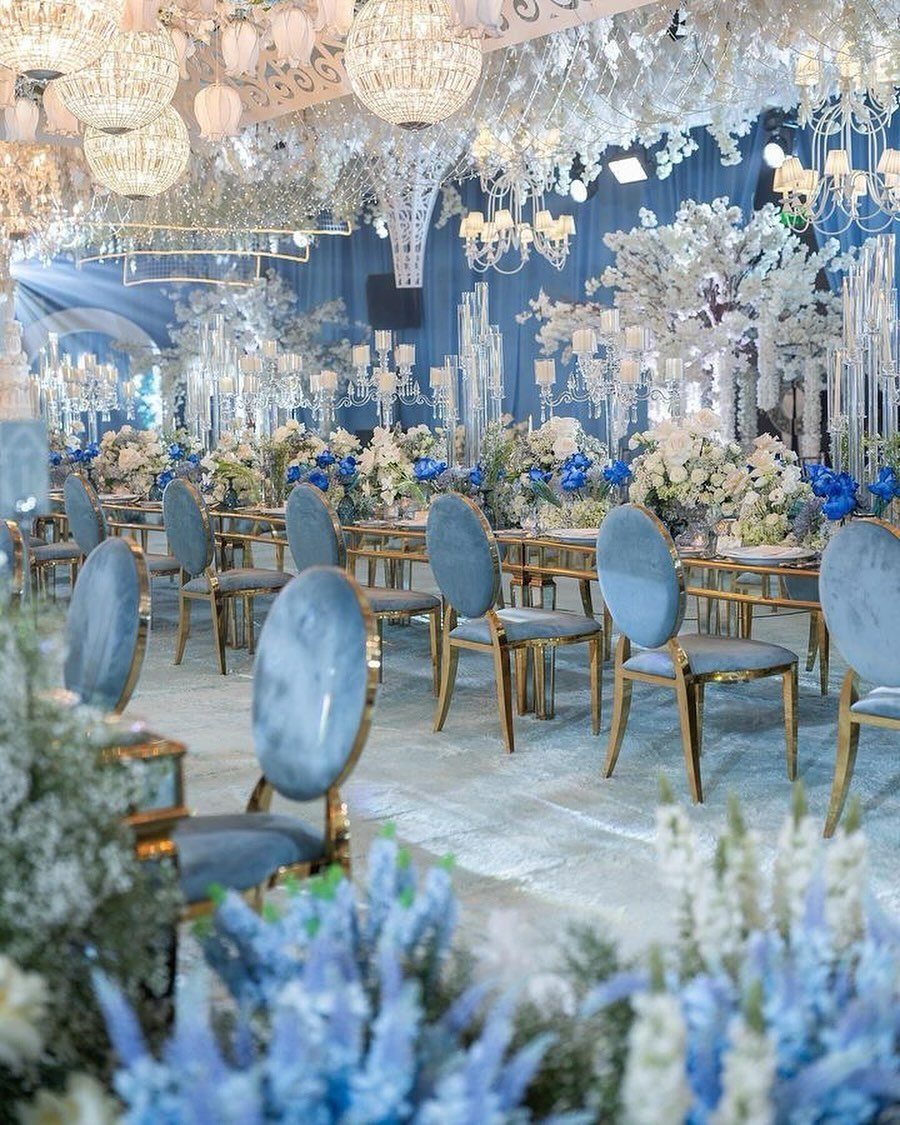 Light blue velvet chairs and floral centerpieces arranged for a winter themed wedding reception.
