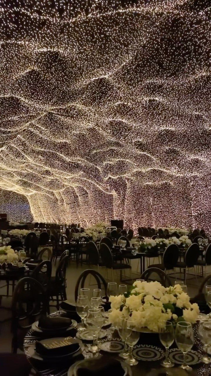 Twinkling fairy lights draped across a ceiling over a formal wedding reception dining area.