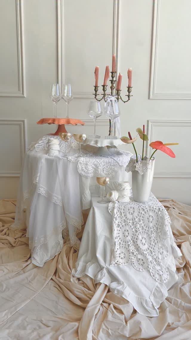 White lace doilies and tablecloths decorating a vintage wedding table setting with candles and flowers.