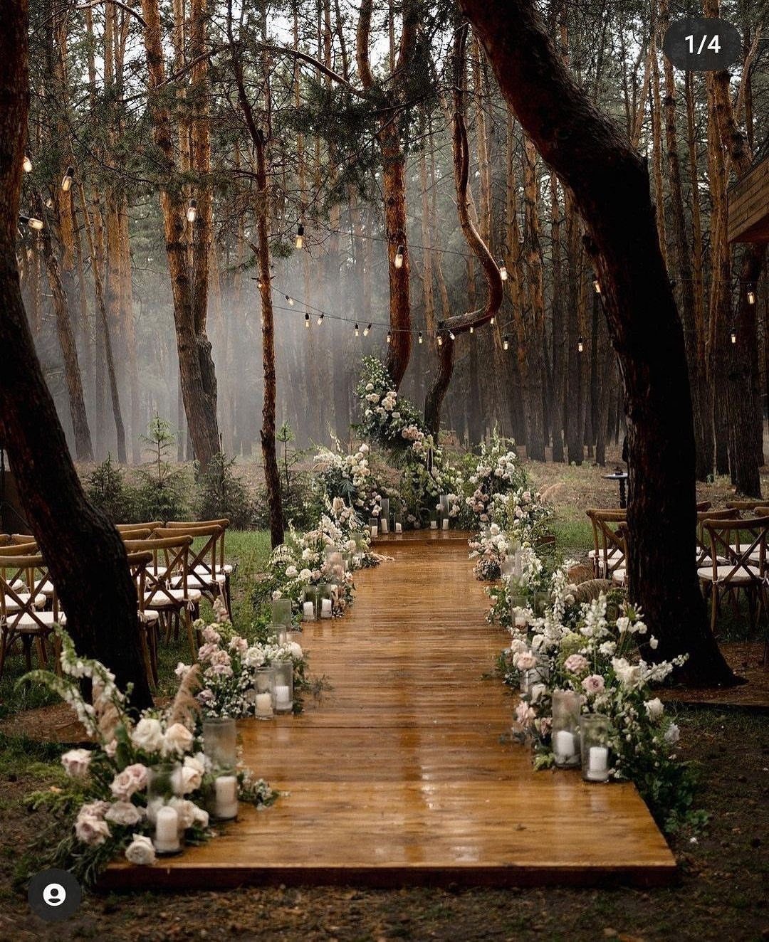 Wooden forest aisle decorated with white and pink wildflower arrangements and glowing candles.