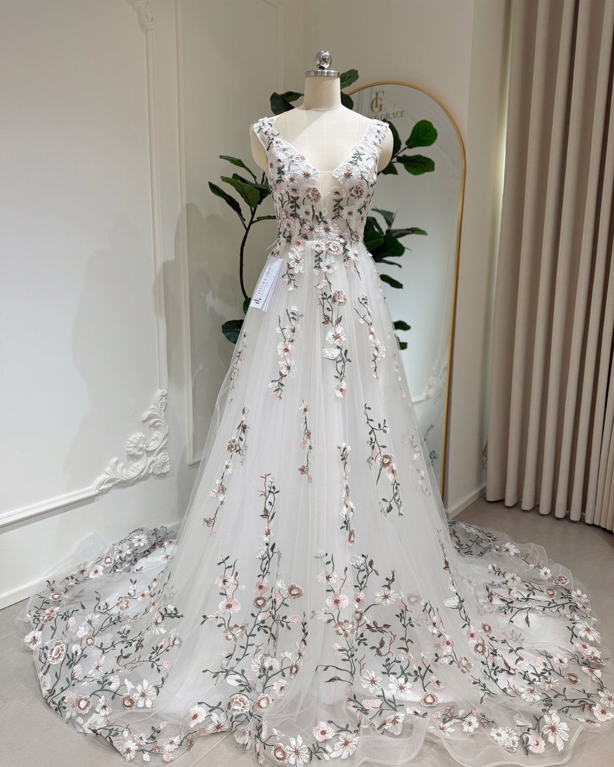 White wedding dress with pink floral embroidery displayed on a mannequin.