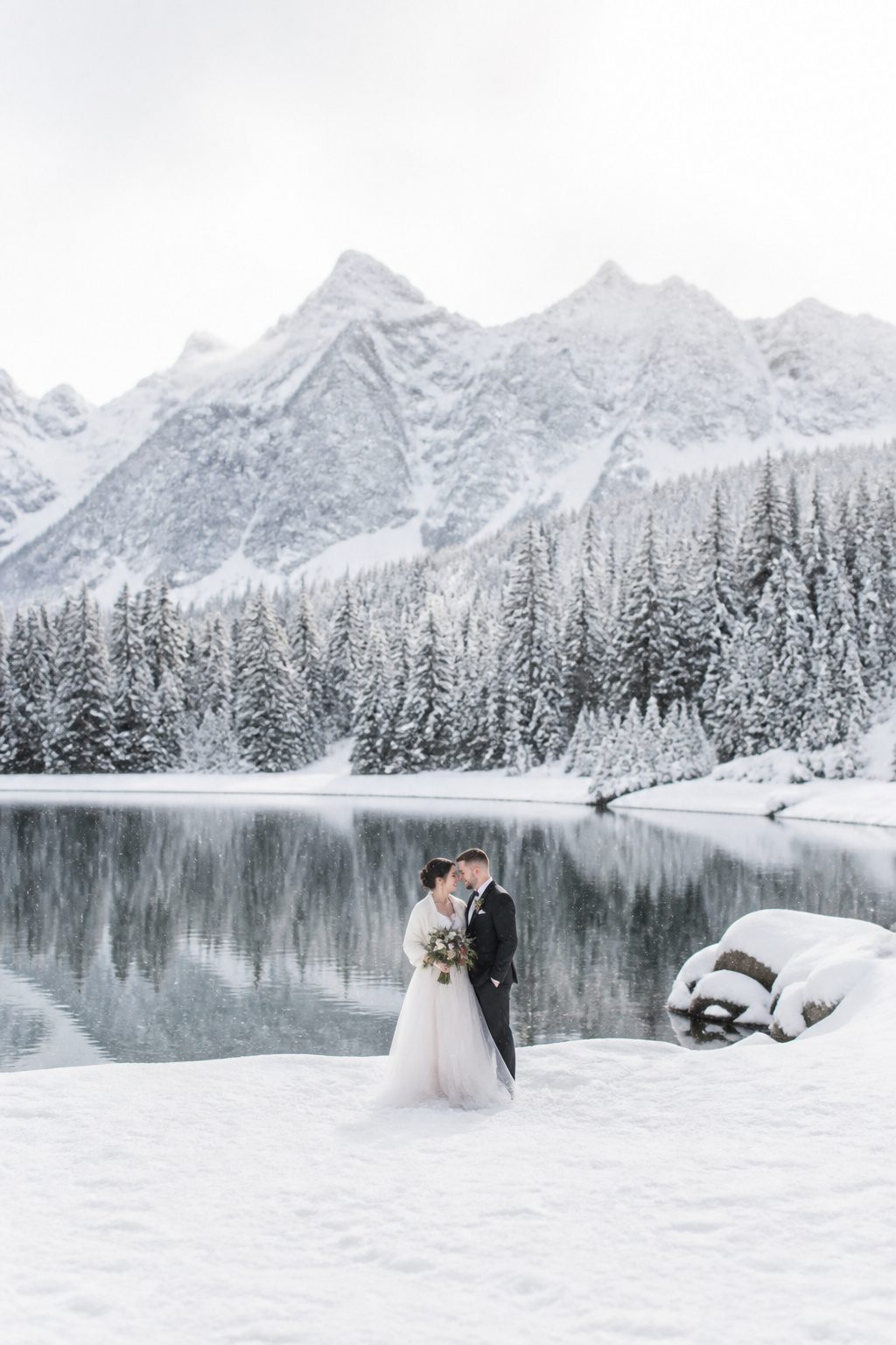 A couple posing for portraits in the snow.